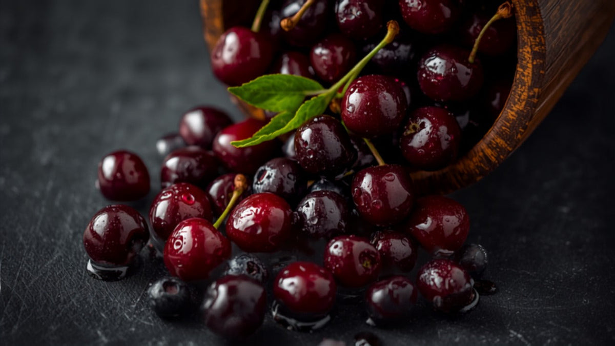 Fresh dark cherries and mixed berries spilling from a wooden bowl onto dark slate, for an article on quercetin and uric acid